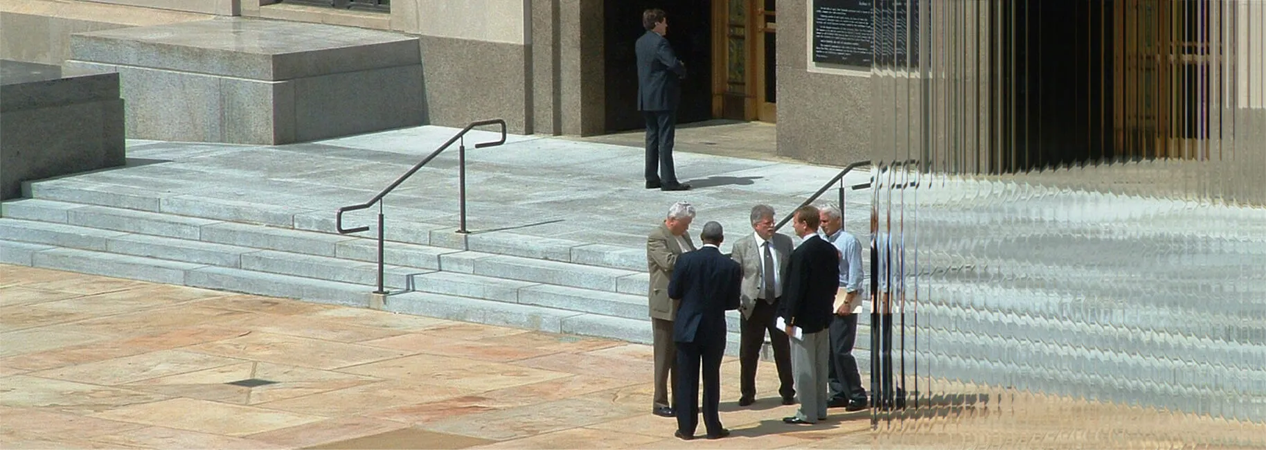 Professionals gathered on a stone plaza outside a glass office building