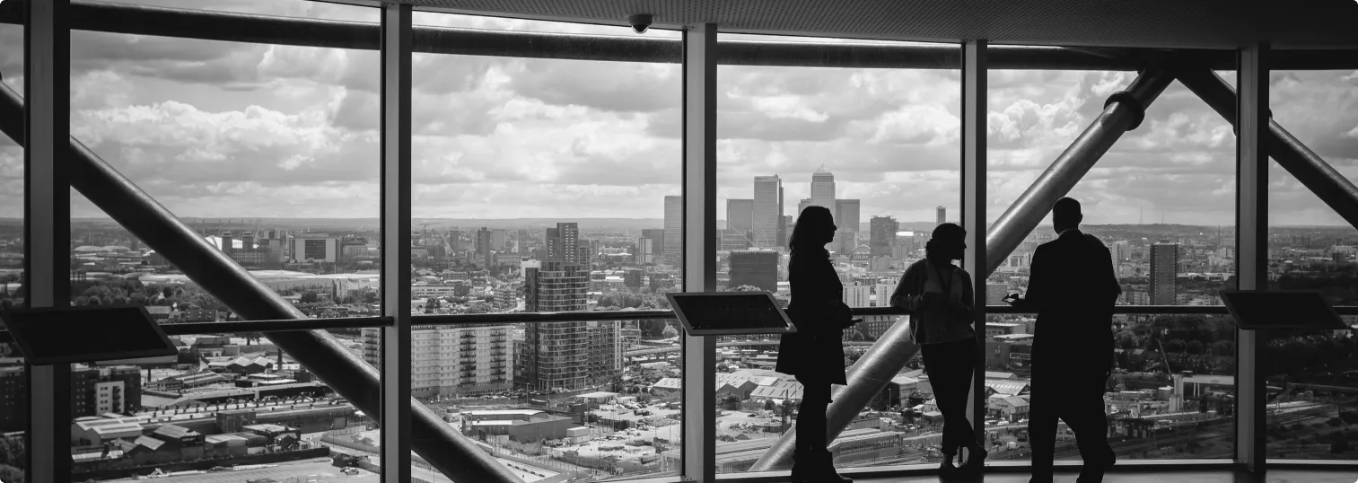 Silhouettes looking out over a city skyline through floor-to-ceiling windows