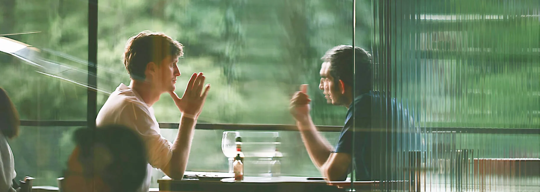 Two colleagues in conversation, seen through a glass facade with city reflections