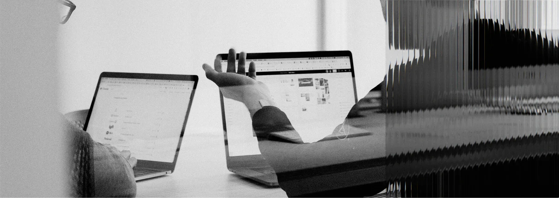 Two colleagues working together on laptops in an office.