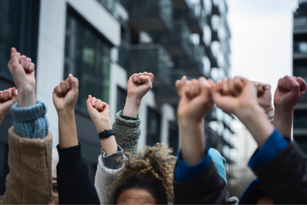 People raising fists in solidarity in front of apartment buildings